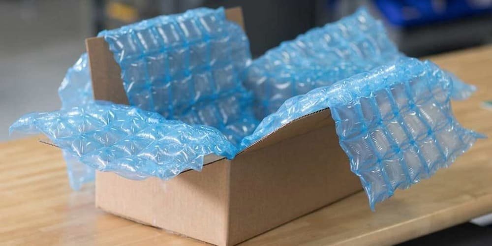 Open cardboard box lined with blue packing air cushions on a wooden table