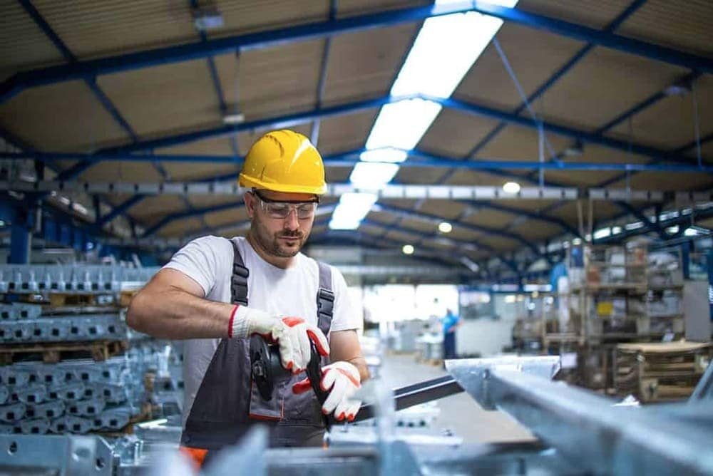 A worker in a hard hat using a tool in an industrial warehouse