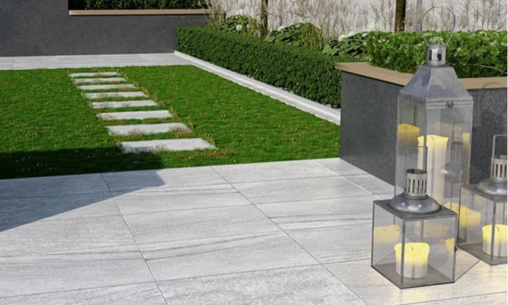 Modern garden with a tiled area, grass, stone pathway, and lanterns