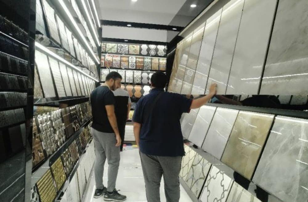 Two people in a tile store examining various decorative tiles on display