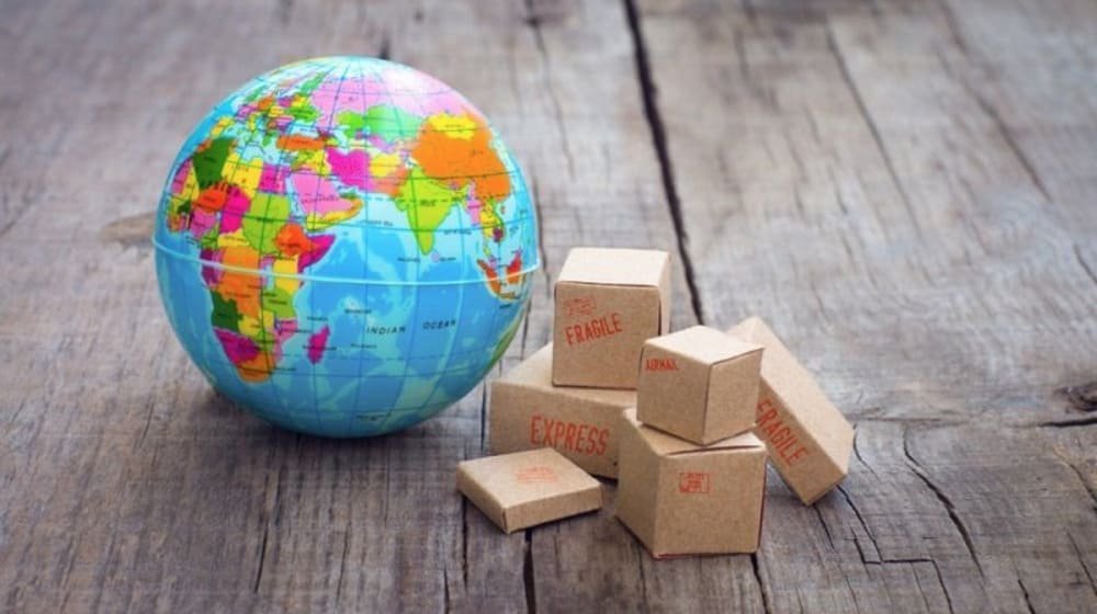 Colorful globe beside fragile express shipping boxes on wooden table