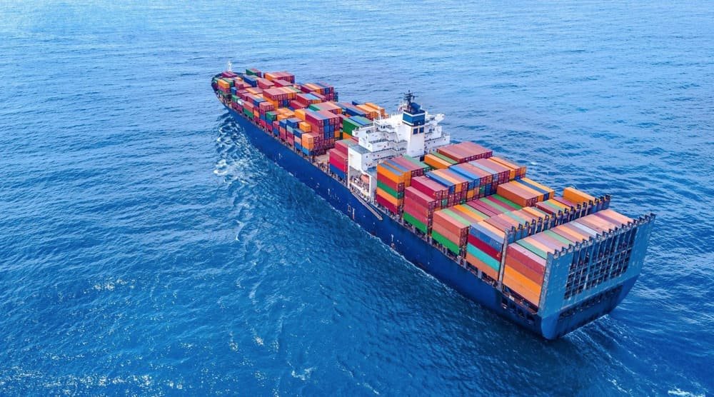 A large container ship at sea, loaded with colorful shipping containers