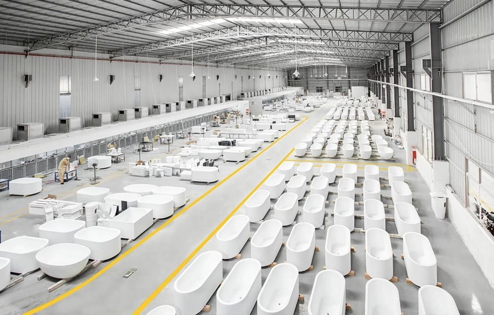 Interior of a large warehouse with rows of white bathtubs neatly arranged on the floor