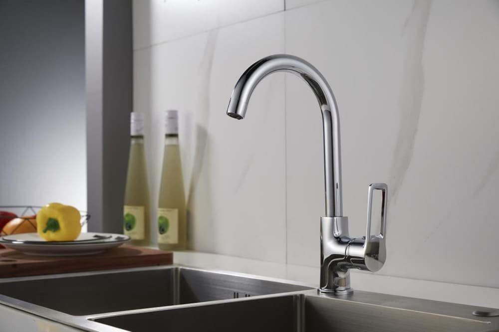 Modern chrome kitchen faucet over a stainless steel sink with bottles and a yellow pepper on the side