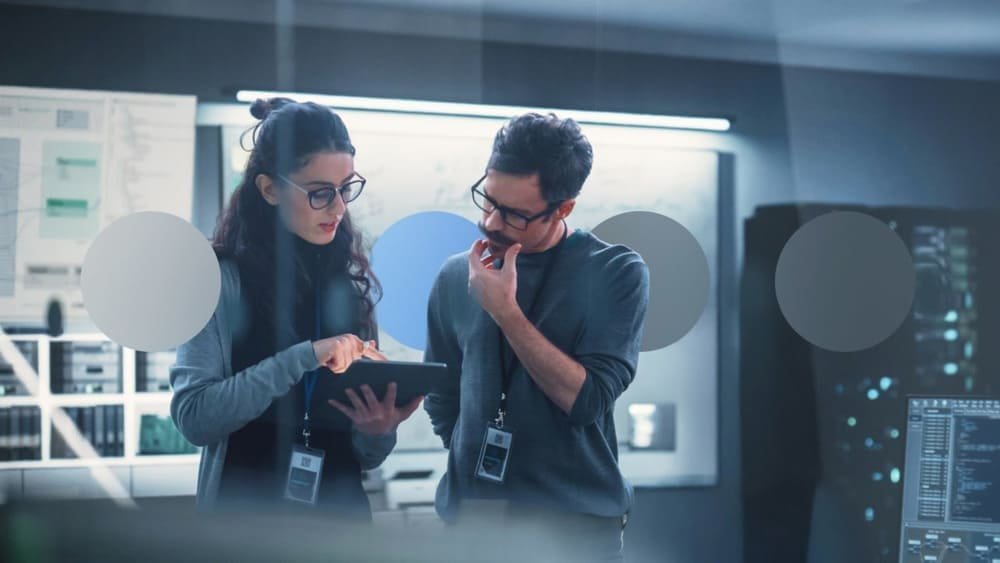 Two people discussing something on a tablet in a modern office setting