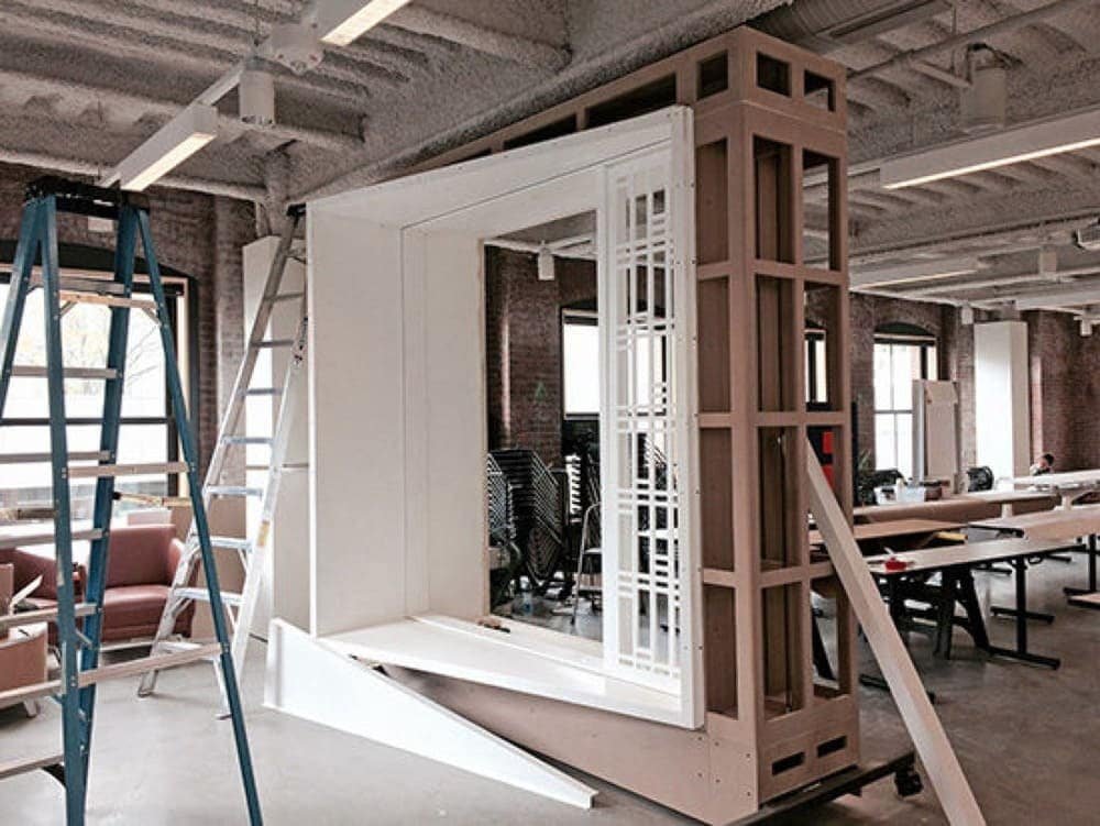 Interior workspace with a partially constructed wooden structure and a ladder