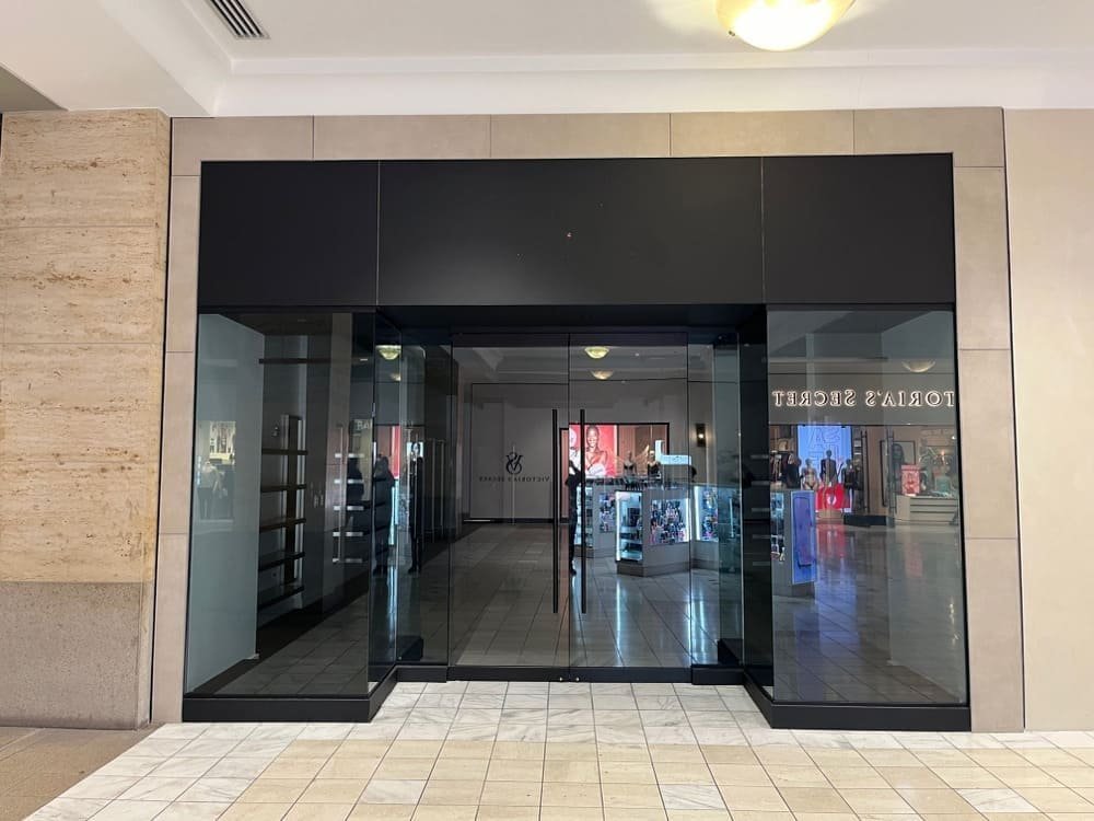 Entrance to a retail store with glass doors and non-slip flooring in a mall