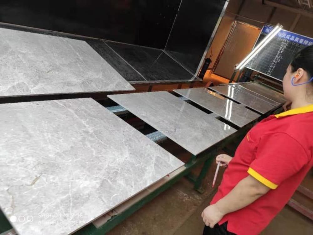 Person inspecting light gray tiles on a conveyor