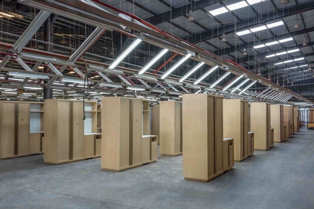 Interior of a large industrial space with rows of wooden storage units and fluorescent lighting overhead