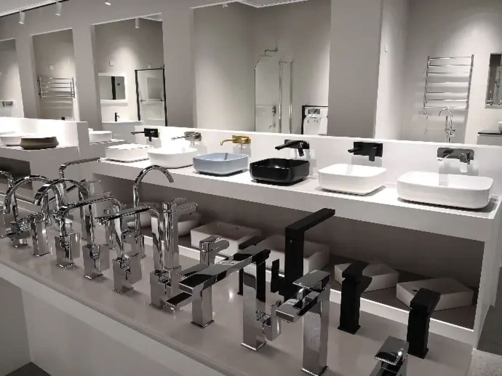 A showroom displaying various modern faucets and bathroom sinks in front of mirrors