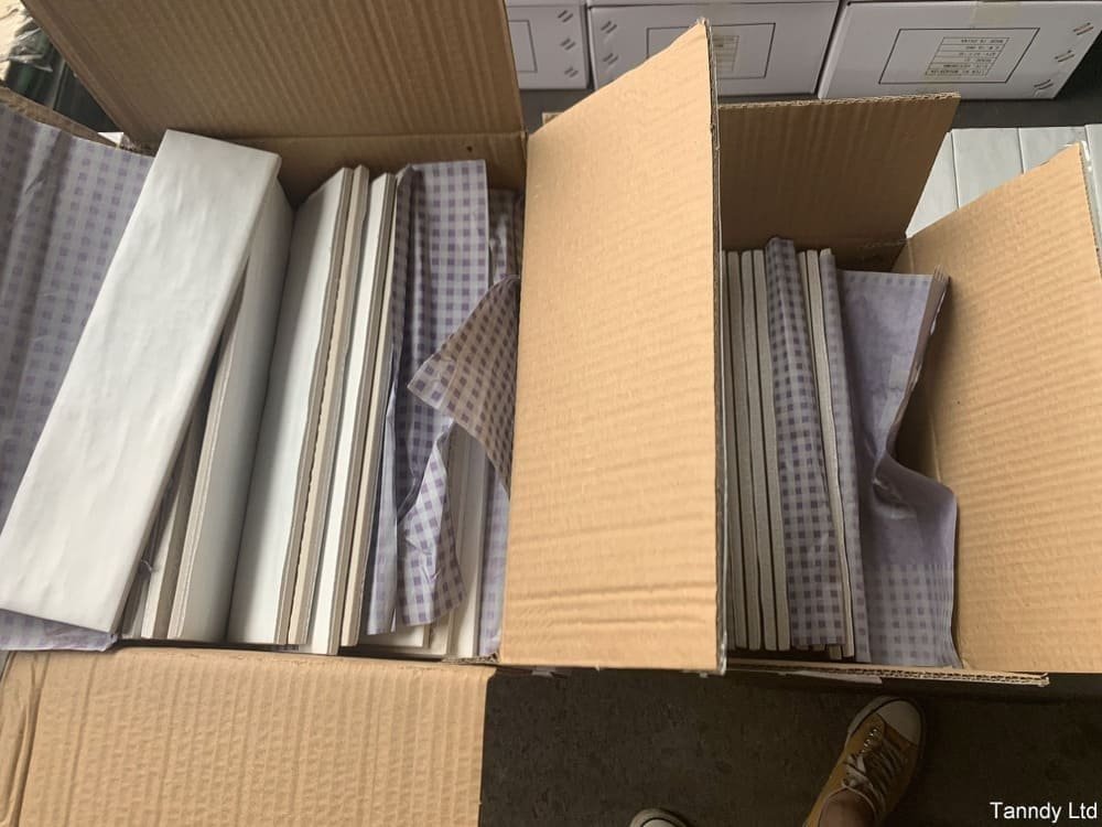 Open boxes of white tiles lined with checkered paper