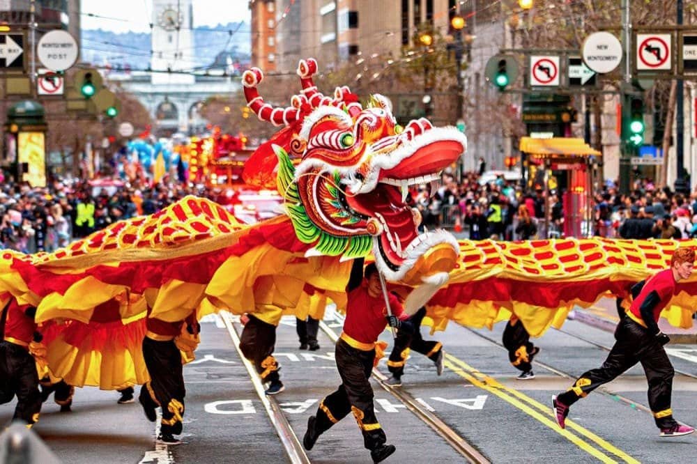 Dragon dance parade with red and yellow performers on a busy city street