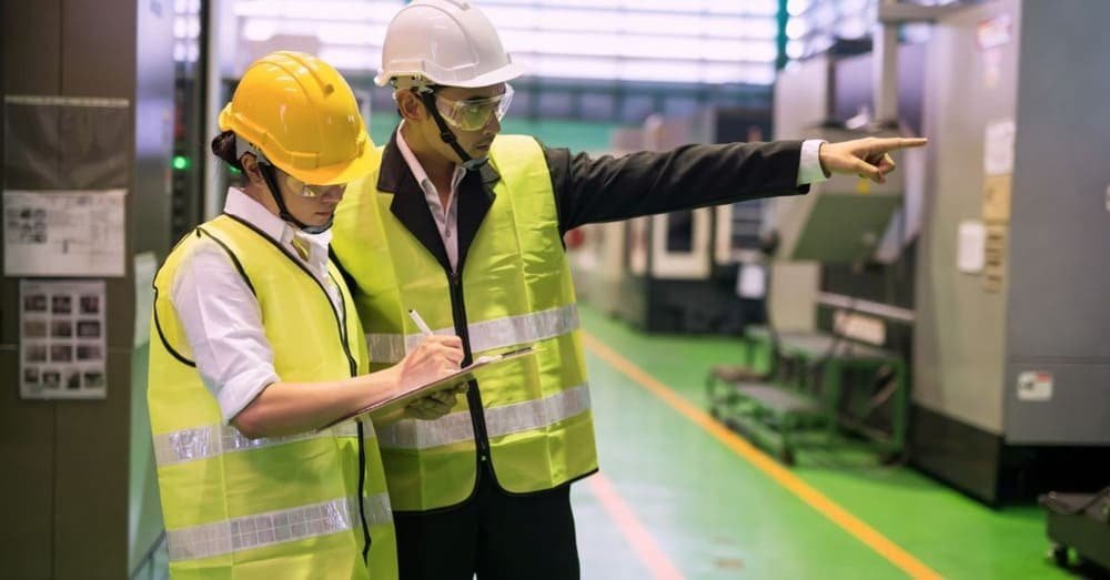 Factory audit in progress with two workers reviewing checklist in production area