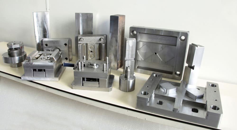 Metal molds and precision machined parts on white surface