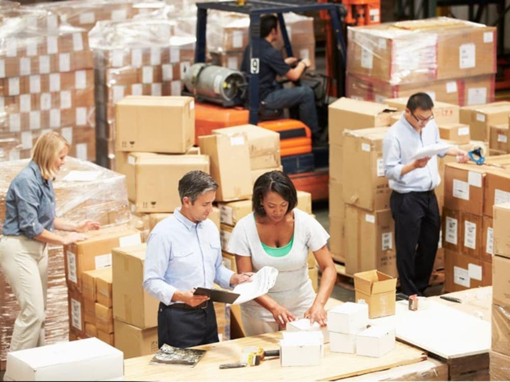 Warehouse team kitting and labeling cartons for bulk orders