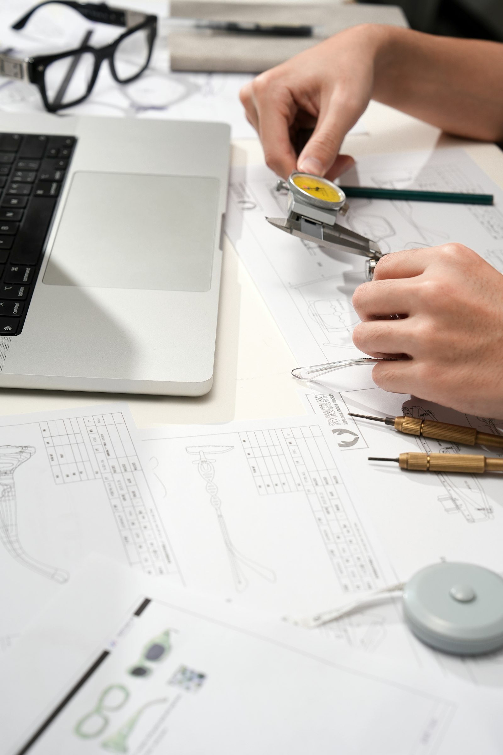 Designer using a dial caliper to check a prototype against technical drawings