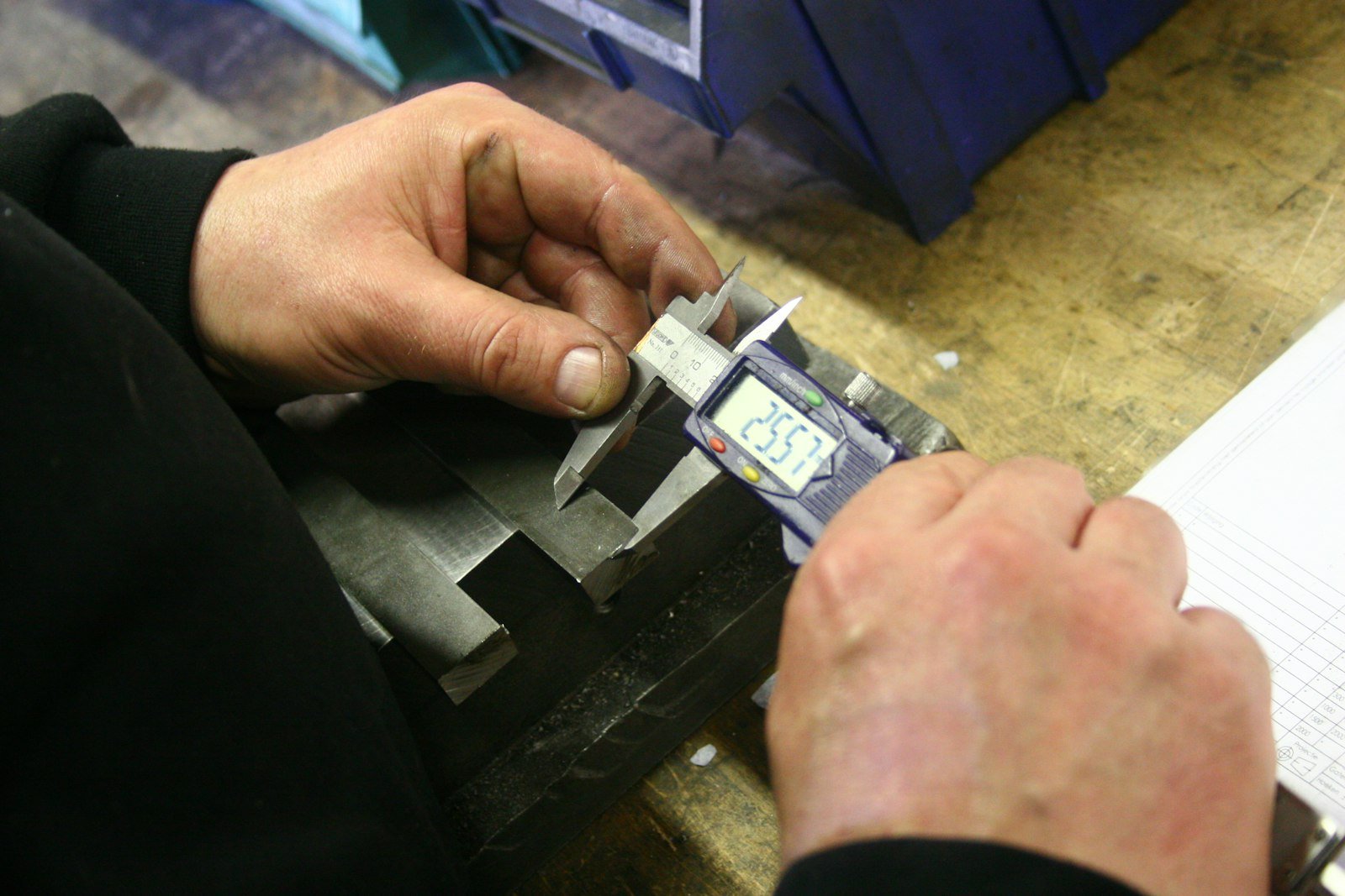 Hands using a digital caliper to measure a metal component