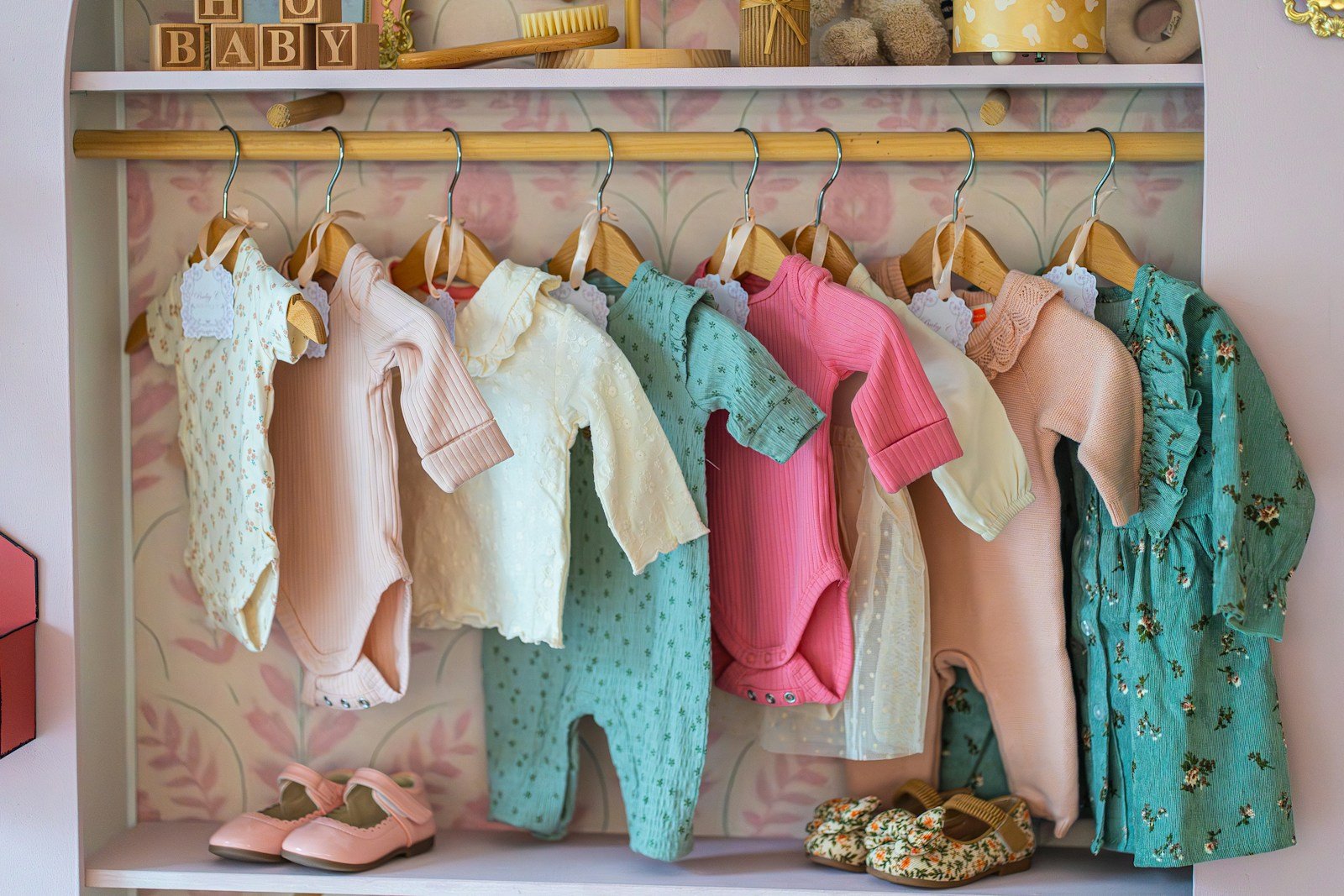 Babywear and kidswear garments in pastel colours hanging neatly on wooden rack
